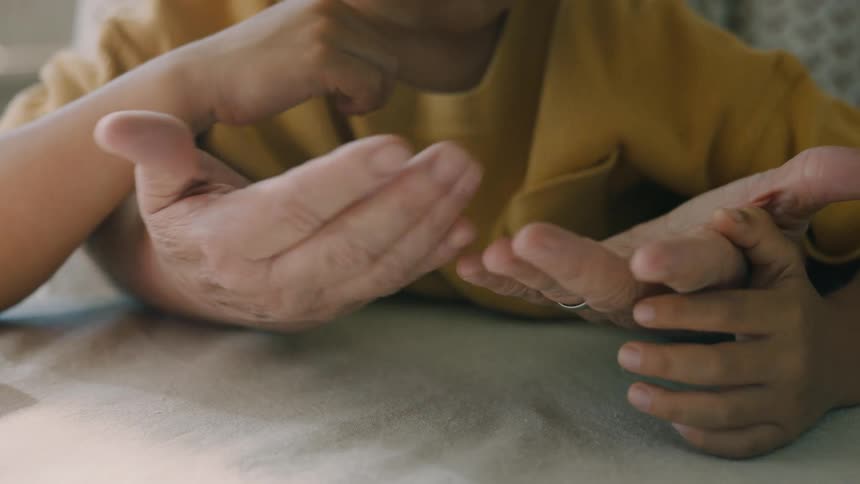 A grandmother is touching her grandsons hands