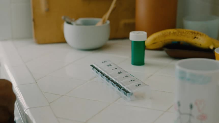 A man takes pills from the pill box