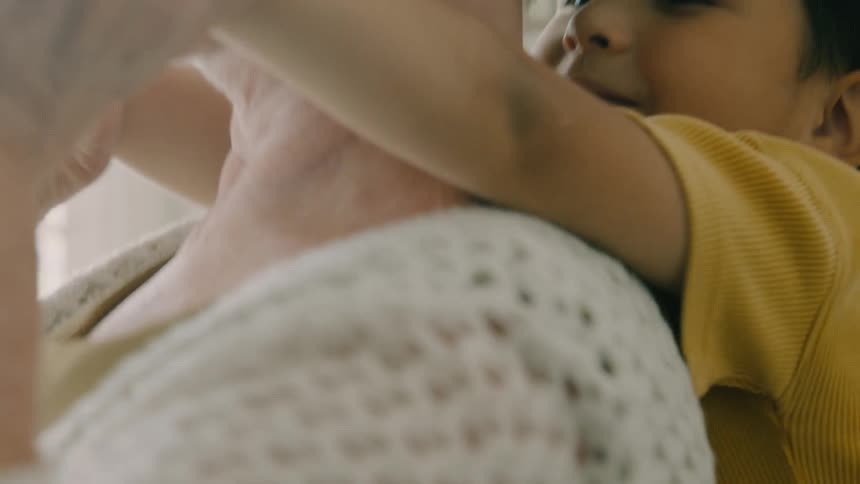 An elderly woman and a boy playing with the boy hugging his grandmother
