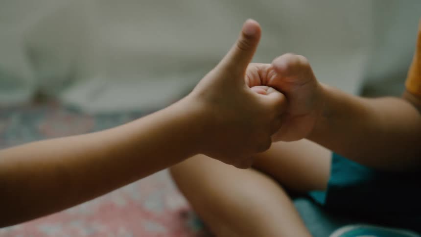 Kids thumb wrestling sitting on the floor in thier bedroom