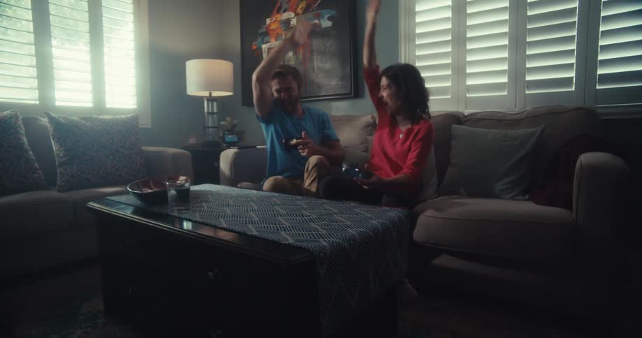 A man and woman are using controllers to play videogames
