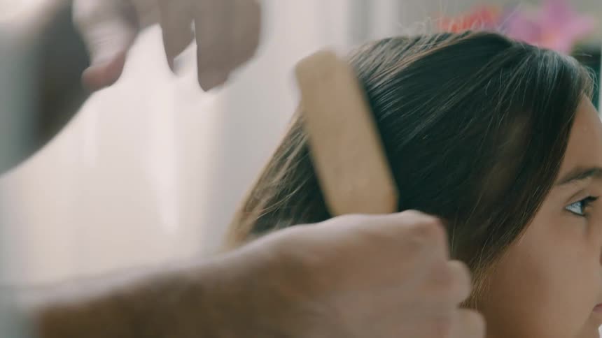 A man is brushing his daughters hair