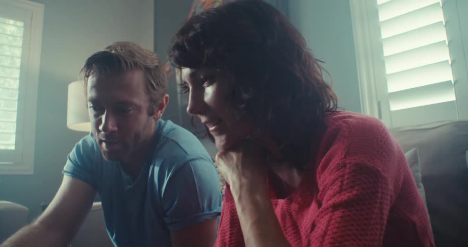 A couple interacts while looking at a laptop screen