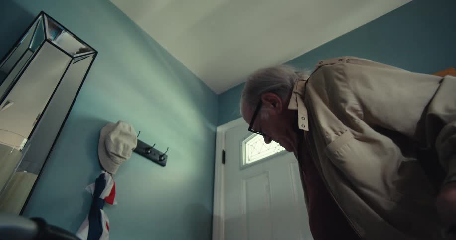 An elderly man entering his house and closing the door walking with the help of a walker