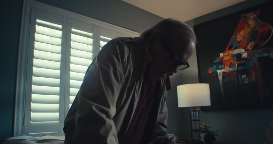 A man enters through the door and sits down on the couch