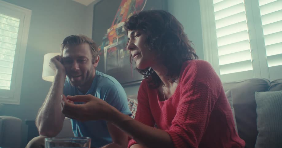 A man and woman sit and talk in front of a computer