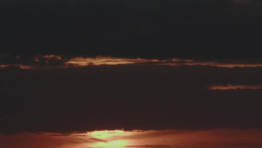 Bright orange solar lights between clouds in a partially dark sky