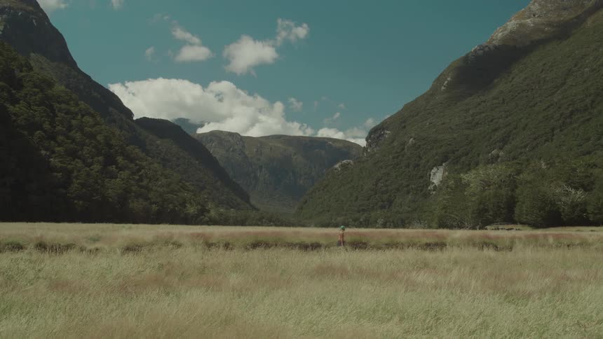 A person is hiking on the field by the mountains
