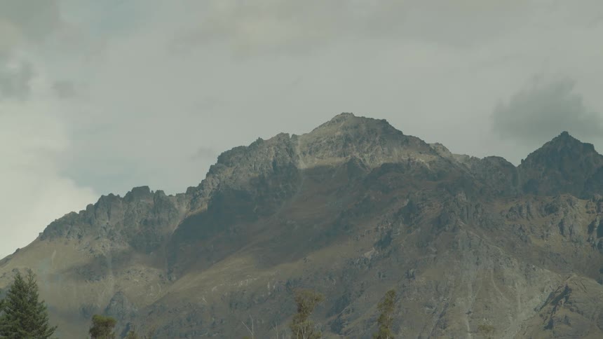 Jagged mountain peaks rise beneath a moody overcast sky