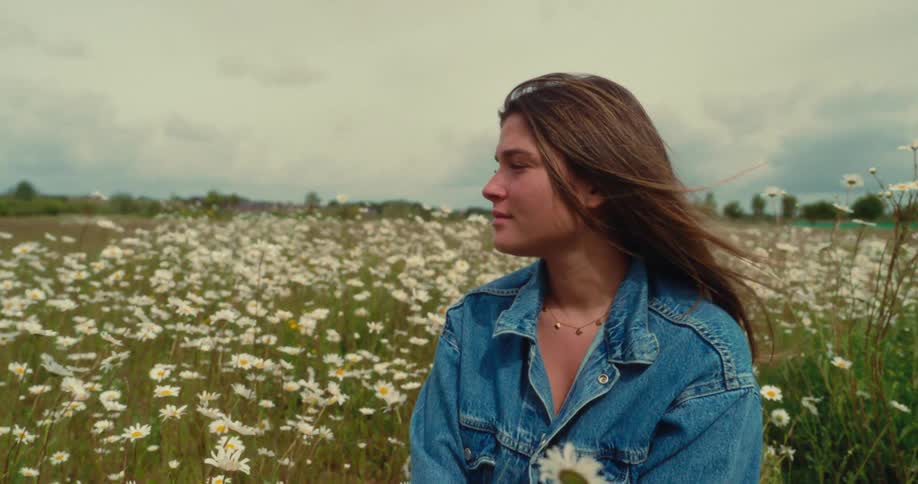 A young woman standing still in a flower field admiring the beauty of nature