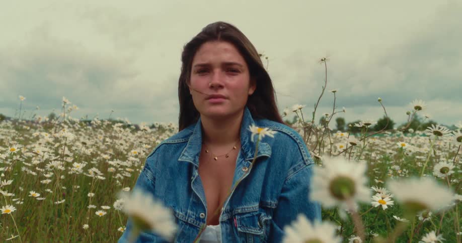 A girl sits in a field of flowers