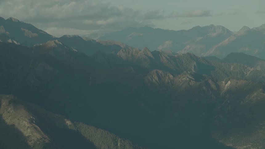 A wide aerial shot of rugged mountain peaks under soft daylight