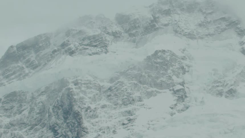Snowy mountain peak partly hidden by mist in icy landscape