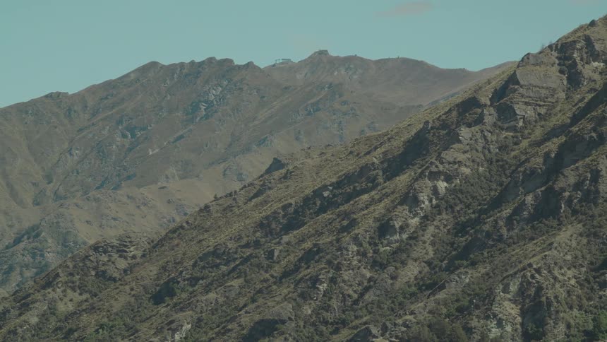 A view of rugged sparsely vegetated mountains stretches across the landscape under a clear blue sky