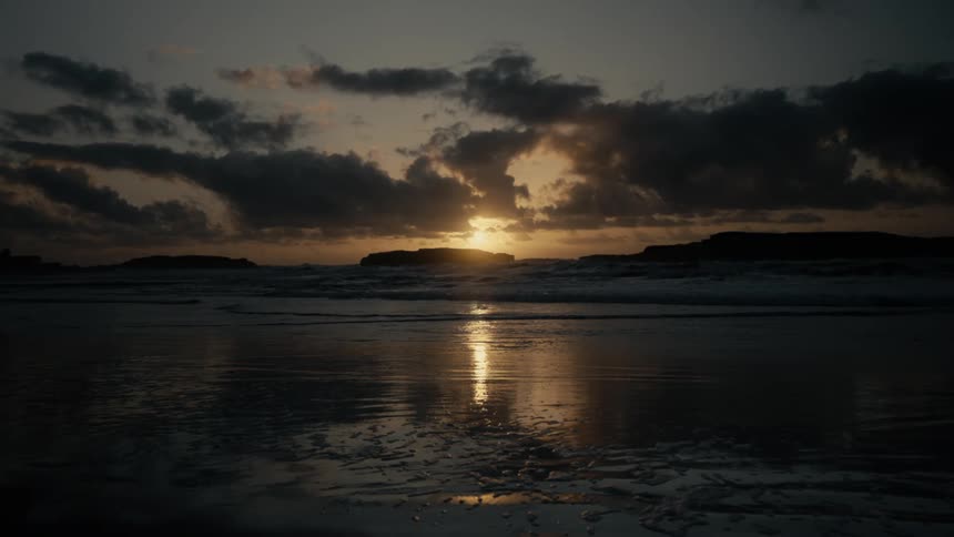 The sun is coming up over a calm body of water in a coastal area