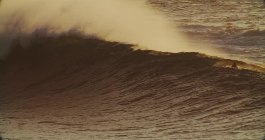 A couple men on surfboards start to catch a large wave then back off