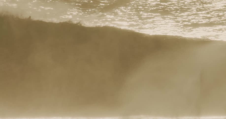 The sunlight shines on the falling wave