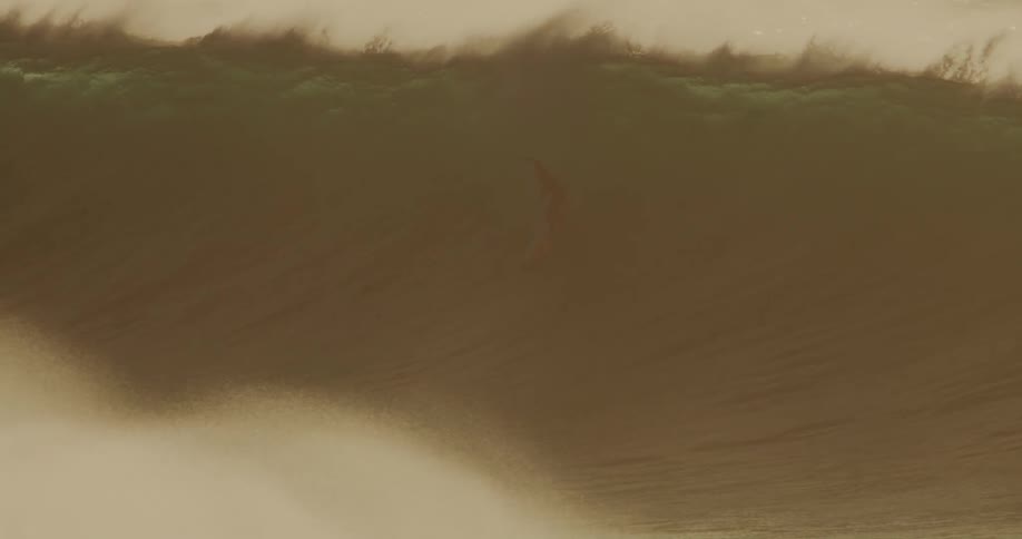 A surfer rides a very large wave