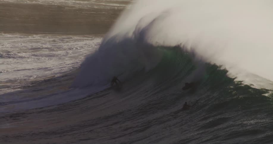 A row of surfers ride a large wave together