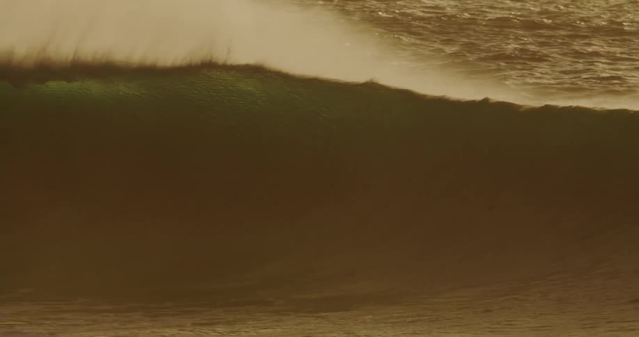 A man looks back at the big wave then rides it on his surfboard
