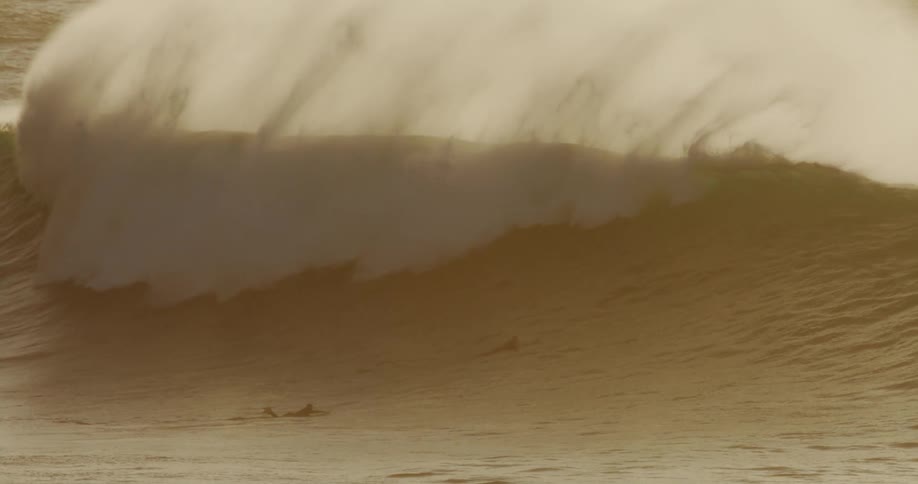 Surfers get covered by a huge wave