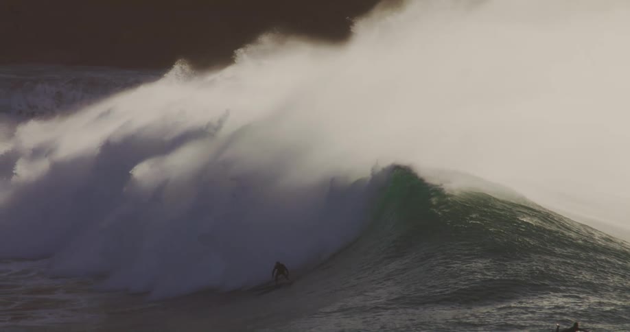 A surfer catches a huge wave
