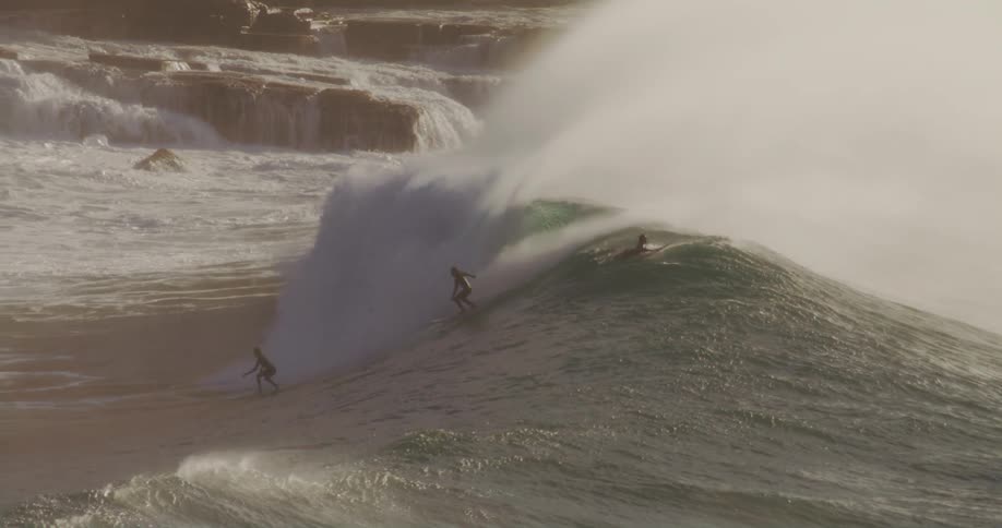 Two surfers are riding the same big wave