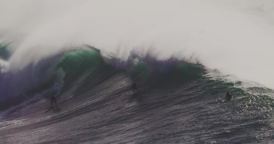 Several surfers ride a big wave