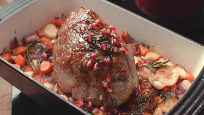 Person cooking a roast bastes the meat with a spoon
