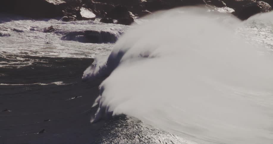 Surfers are paddling towards a large crashing wave