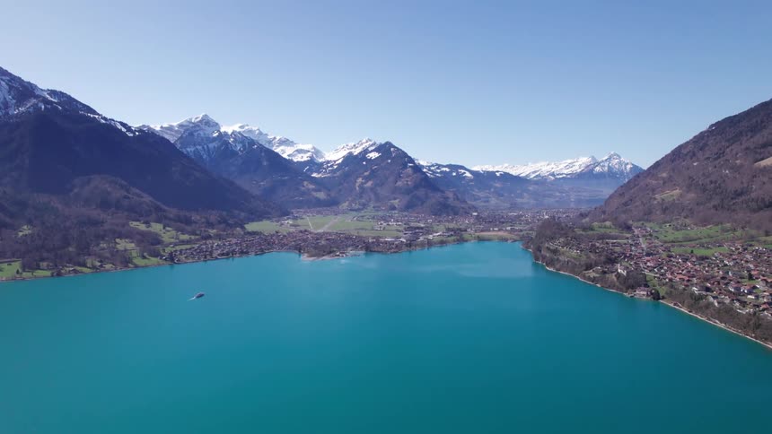 An aerial view of a lake with mountains in the distance and houses on one shore