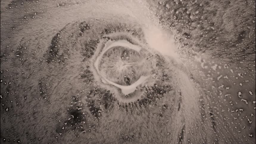 Closeup of abstract swirling black and white liquid forming a craterlike pattern