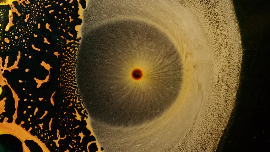 Yellowish liquid and organic matter collapsing against a black background