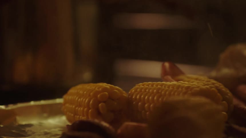 Crab being placed on a plate with cooked corn