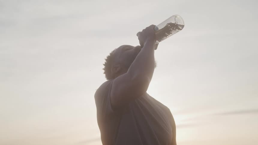 Man drinking water from a bottle outdoors