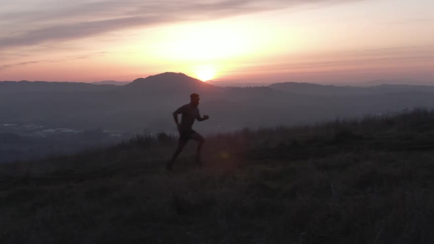 A man is running uphill at sunrise
