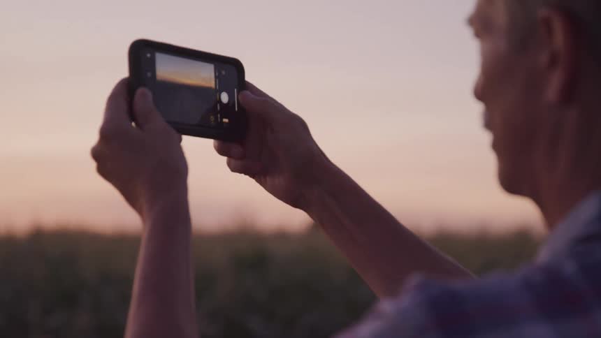 A man holds a smartphone horizontally and takes a picture of the horizon