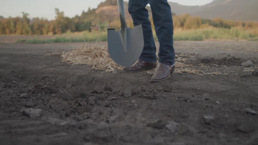 The farmer is digging with a shovel