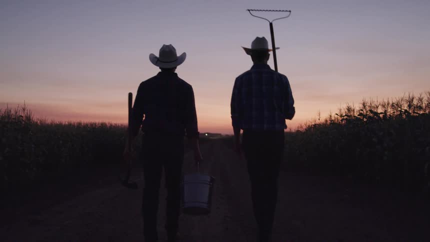 Two farmers carry equipment together