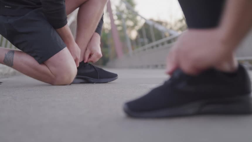 Two people are tying their shoes on the bridge