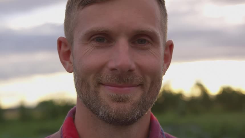 A man smiles while standing outside