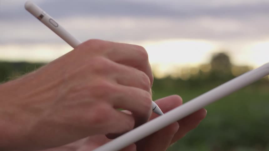 A person writes on a tablet outside