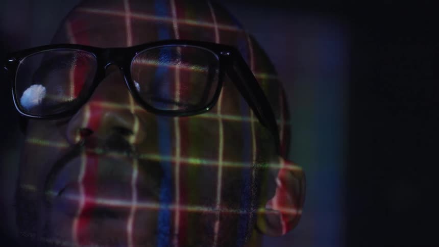 A man sits with a projection overlaid on his face
