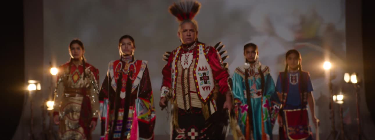 Native american group stands confidently in traditional attire on stage