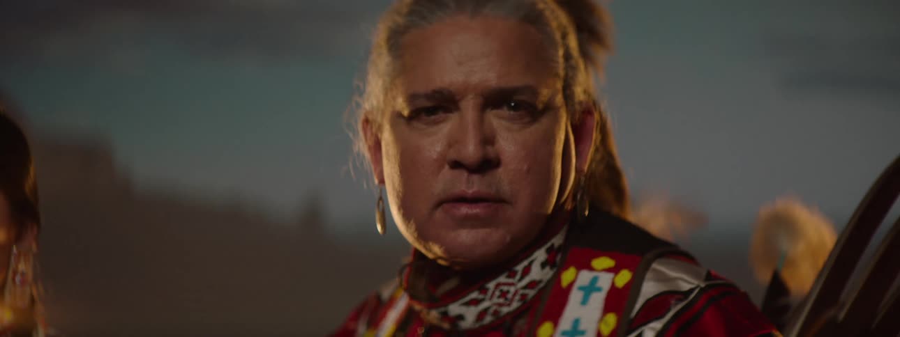 An american indian wearing traditional native attire stands on a stage proudly representing their cultural heritage