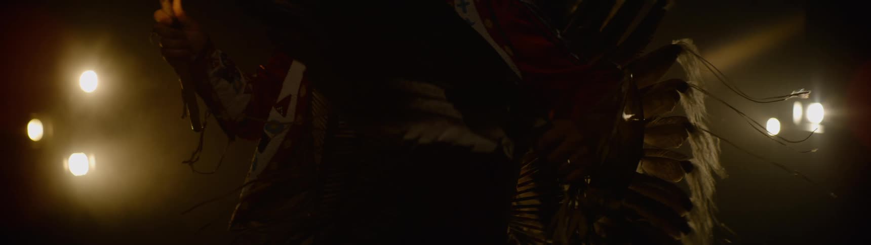 An individual wearing traditional american indian attire proudly showcasing it on a stage