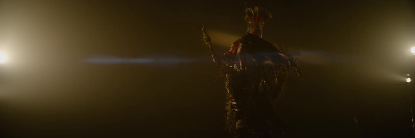 The costumed man is dancing in the dark