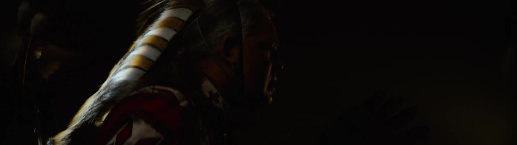 Silhouette of a man in a lowlight environment wearing traditional indigenous clothing