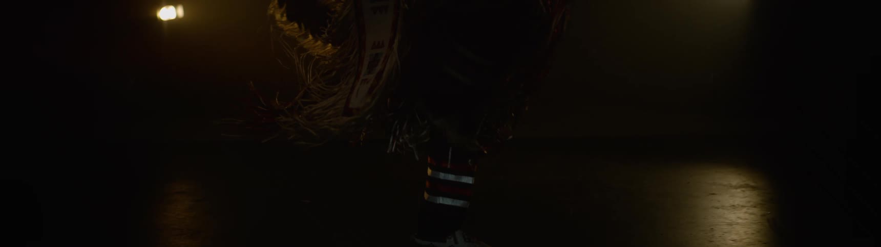 A performer is dancing on the dark stage