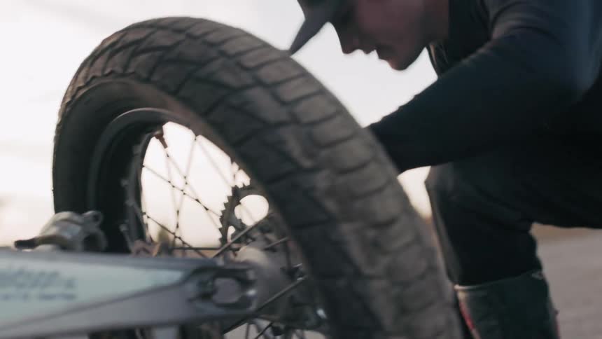 Man with tools adjusting a motorcycle wheel